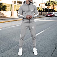 a man is standing on the street in a grey tracksuit